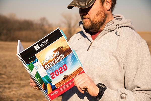 ag producer reading On-Farm Research on a clear harvest day